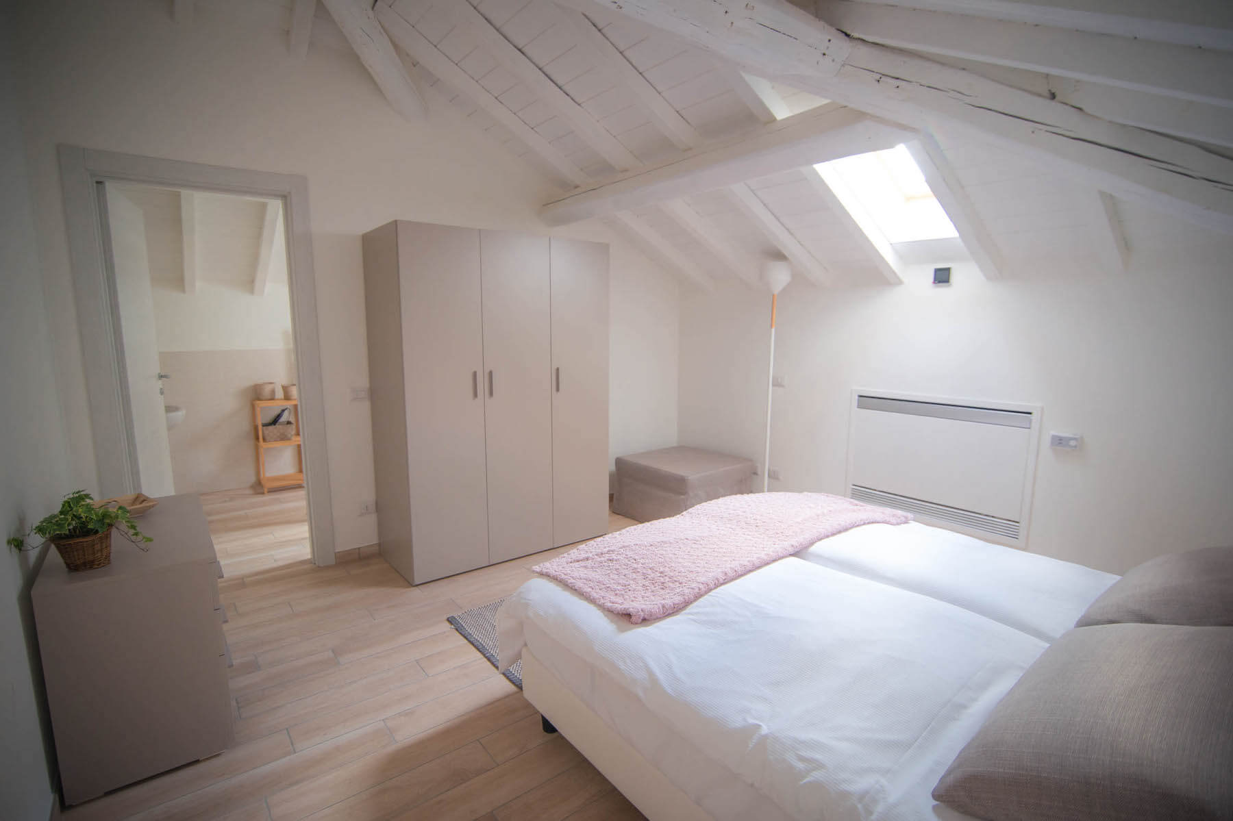 appartamento per vacanze con letto, armadio, cassettiera bassa e soffitto a tetto bianco