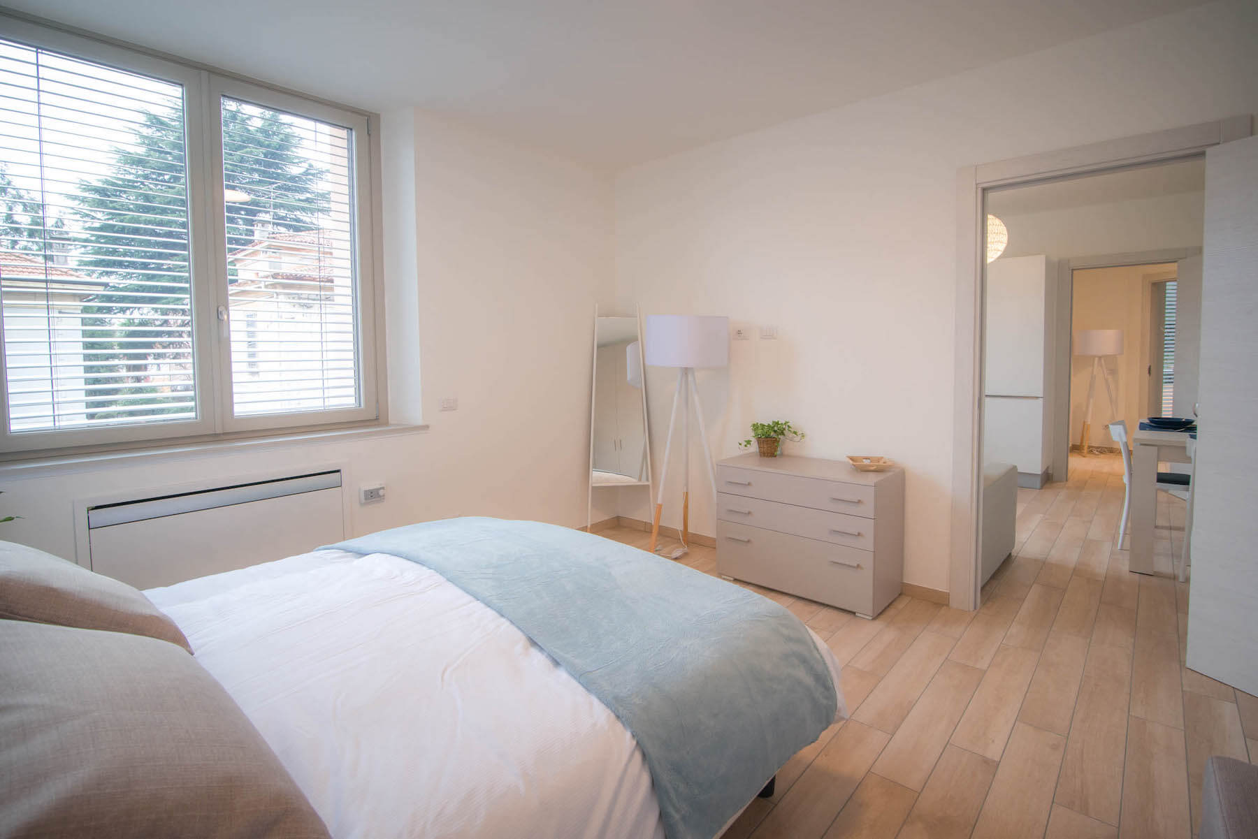 Camera da letto con letto, specchio, lampada, cassettiera, finestra ed elementi decorativi